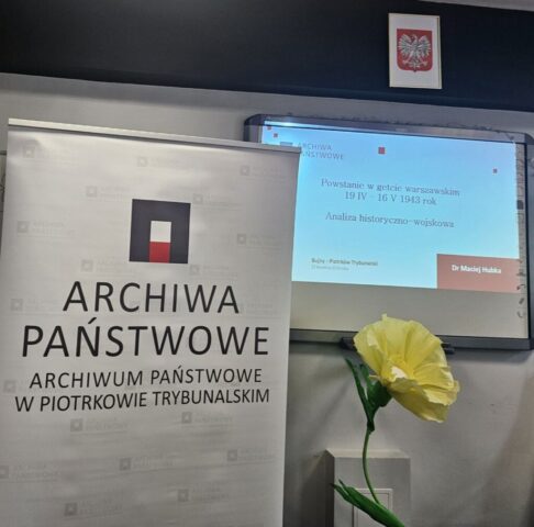 Sala z ekranem i banerem podczas prezentacji historycznej.