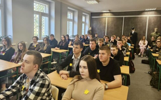 Uczniowie siedzą w sali wykładowej podczas prezentacji.