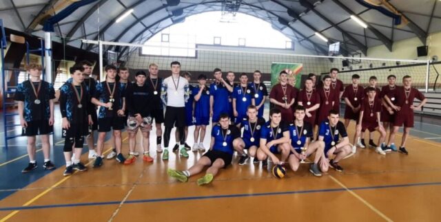 Trzy drużyny siatkarskie w różnych strojach pozują wspólnie w hali sportowej; część zawodników trzyma puchary, a wielu ma medale na szyjach.