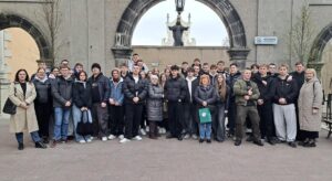 Grupa uczniów i nauczycieli stoi przed kamiennym wejściem z dwoma łukami podczas wycieczki szkolnej.