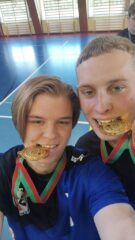 pilka_nozna_halowa02 Dwóch zawodników szkolnej drużyny piłki nożnej w hali sportowej prezentuje zdobyte złote medale.