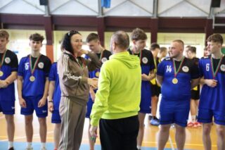pilka_nozna_halowa05 Szkolna drużyna piłki nożnej podczas dekorowania medalami. Na pierwszym planie opiekun drużyny odbiera gratulacje od organizatora.