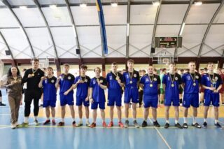 pilka_nozna_halowa10 Zwycięska drużyna szkolna pozuje do zdjęcia z opiekunem w hali sportowej po dekoracji medalami.