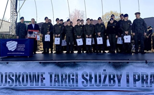 Uczniowie w mundurach stoją na scenie podczas wojskowych targów pracy.