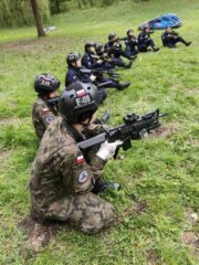 oboz_zloty_potok03 Ćwiczenia taktyczne na polanie — uczestnicy w mundurach wykonują zadania taktyczne na otwartym terenie.