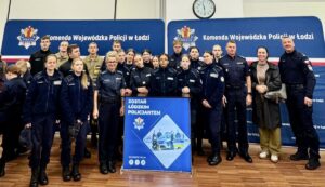 policyjne_targi_pracy_edukacji Uczniowie klasy mundurowej pozują do zdjęcia z Funkcjonariuszami i opiekunami na tle banerów Komendy Wojewódzkiej Policji w Łodzi.