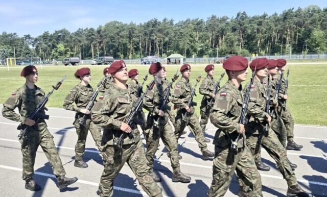 Żołnierze w mundurach maszerują w szyku podczas wydarzenia wojskowego.