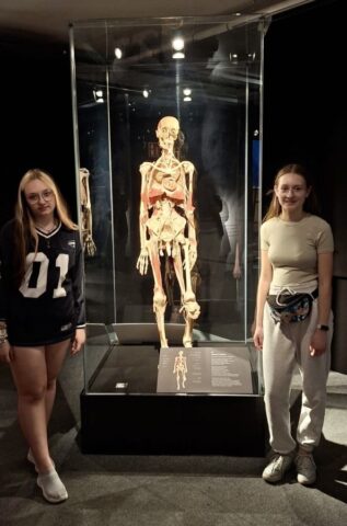 Dwie kobiety stoją przy modelu szkieletu człowieka na wystawie Body Worlds.