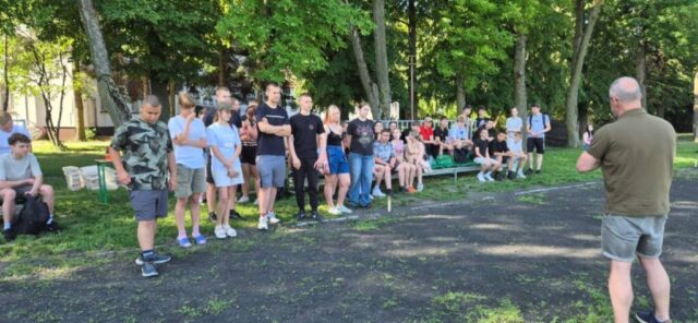event_proekologiczny04 Grupa osób słucha prowadzącego podczas krótkiego omówienia w plenerze.