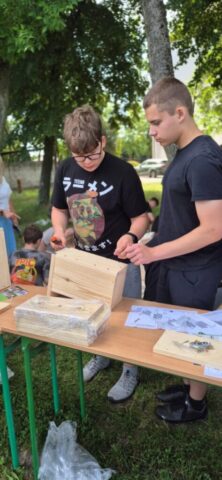 event_proekologiczny08 Dwie osoby pracują przy stole, skręcając drewniane elementy według instrukcji.