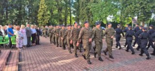 Rozpoczecie_roku_szkolnego6 Dwie grupy w mundurach maszerują w przeciwnych kierunkach, obserwowane przez uczestników wydarzenia.