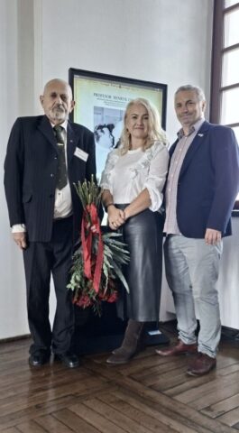 pamiec01 Trzy osoby pozują do zdjęcia na tle planszy poświęconej prof. Henrykowi Gnoińskiemu.