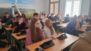 2 nauczycieli i uczniowie siedzący w ławkach podczas zajęć w sali lekcyjnej.