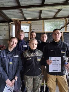 turniej_kbks Sześć osób w strojach służbowych stoi w pomieszczeniu, dwie osoby trzymają dyplomy i puchar.
