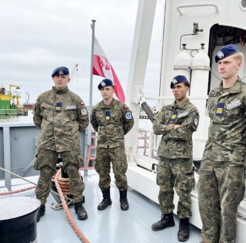 Uczniowie stoją na pokładzie jednostki wojskowej podczas zajęć.