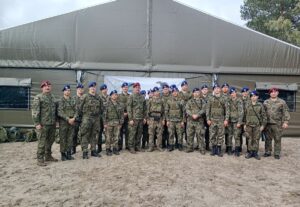 zlot_ustka Uczniowie klas mundurowych wraz z opiekunami i instruktorami pozują do zdjęcia grupowego na tle namiotu wojskowego podczas zajęć szkoleniowych.