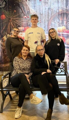 konkursy_su6 Grupa uczniów i nauczycieli pozuje do wspólnego zdjęcia na tle dekoracji tematycznej.