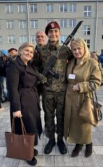 Osoba w mundurze wojskowym w towarzystwie trzech osób podczas uroczystości wojskowej.