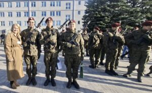 Trzy osoby w mundurach wojskowych oraz osoba cywilna podczas uroczystości przysięgi wojskowej.