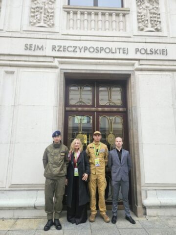 wycieczka_sejm05 Uczestnicy wizyty stoją przed wejściem do budynku Sejmu Rzeczypospolitej Polskiej.