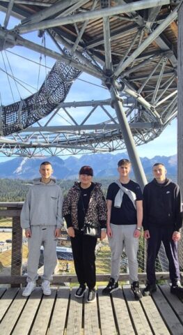 wycieczka_zakopane10 Grupa uczniów wraz z opiekunem na platformie widokowej z panoramą gór.